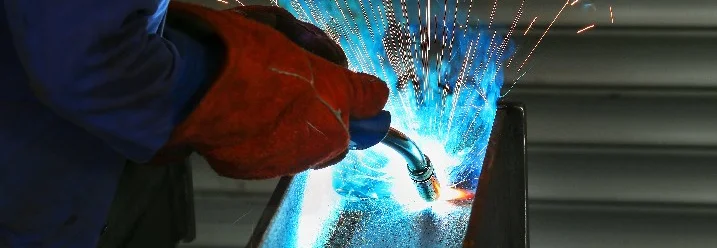 Person schweißt Metall mit Schutzkleidung